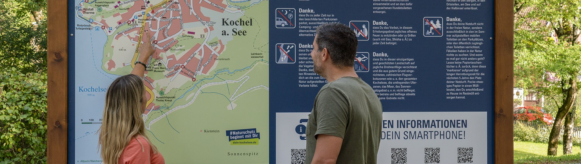 Zwei Personen schauen sich den Ortsplan von Kochel a. See an., © Torusit Information Kochel a. See; Fotograf B. Ritschel Zwei Personen schauen sich den Ortsplan von Kochel a. See an., © Torusit Information Kochel a. See; Fotograf B. Ritschel