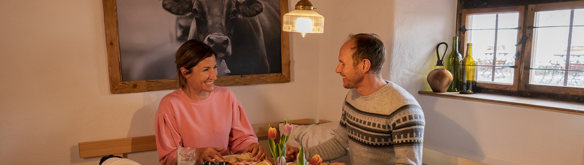 Eine Frau und ein Mann sitzen an einem gedeckten Tisch und unterhalten sich., © Tourist Information Kochel a. See, Fotograf B. Ritschel Eine Frau und ein Mann sitzen an einem gedeckten Tisch und unterhalten sich., © Tourist Information Kochel a. See, Fotograf B. Ritschel