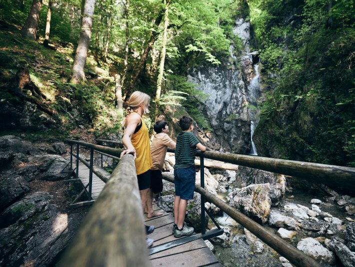 Eine Mutter mit zwei Kindern stehen auf der Br&uuml;cke am Lainbachwasserfall., &copy; TOM, Fotograf Tobias K&ouml;hler